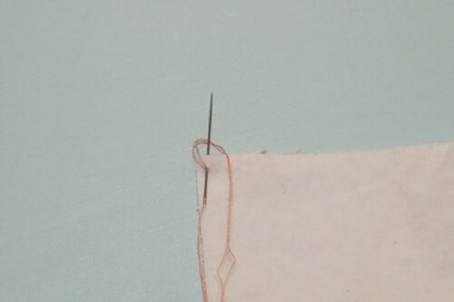 ブランケットステッチのひと針目を刺して、後ろから出した針に糸をかけたところ