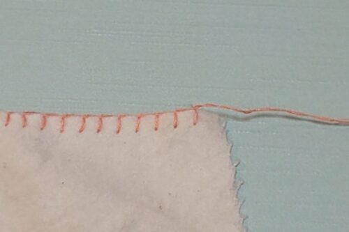 糸を右側に引っ張っている。これから１枚布のブランケットステッチの縫い終わりをするところ