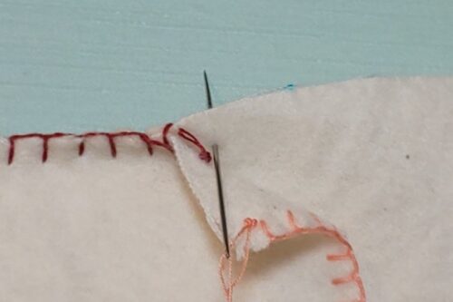 新しい糸を通した針を２枚の生地の間から後ろに出している