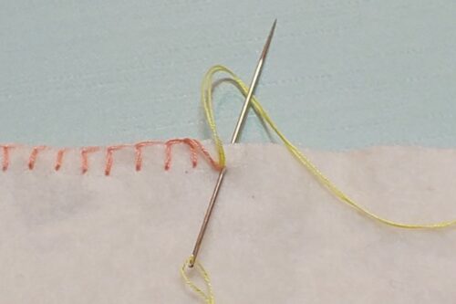 ブランケットステッチの縫いはじめと同じように、後ろに針を通して糸をかけている